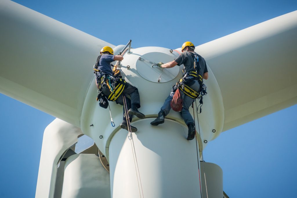 Deux opérateurs de maintenance interviennent sur une éolienne pour en assurer l'efficacité opérationnelle.