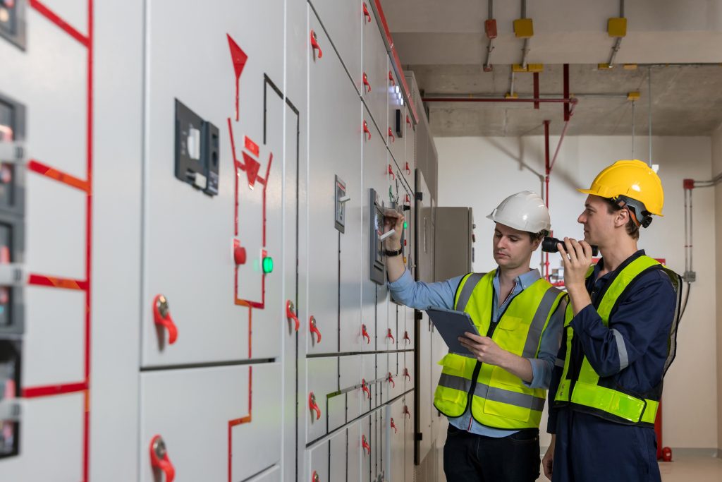 Deux opérateurs de sécurité effectuant la maintenance d'un tableau de distribution pour l'appareillage électrique.