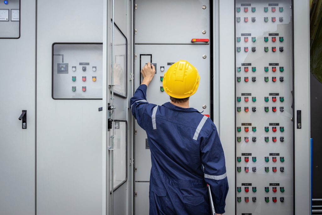 Opérateur travaillant sur un panneau de transmission et de distribution, assurant la fiabilité du réseau électrique.