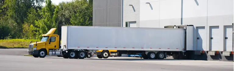 Big rig day cab semi trucks for local deliveries loading and unloading commercial cargo in warehouse dock