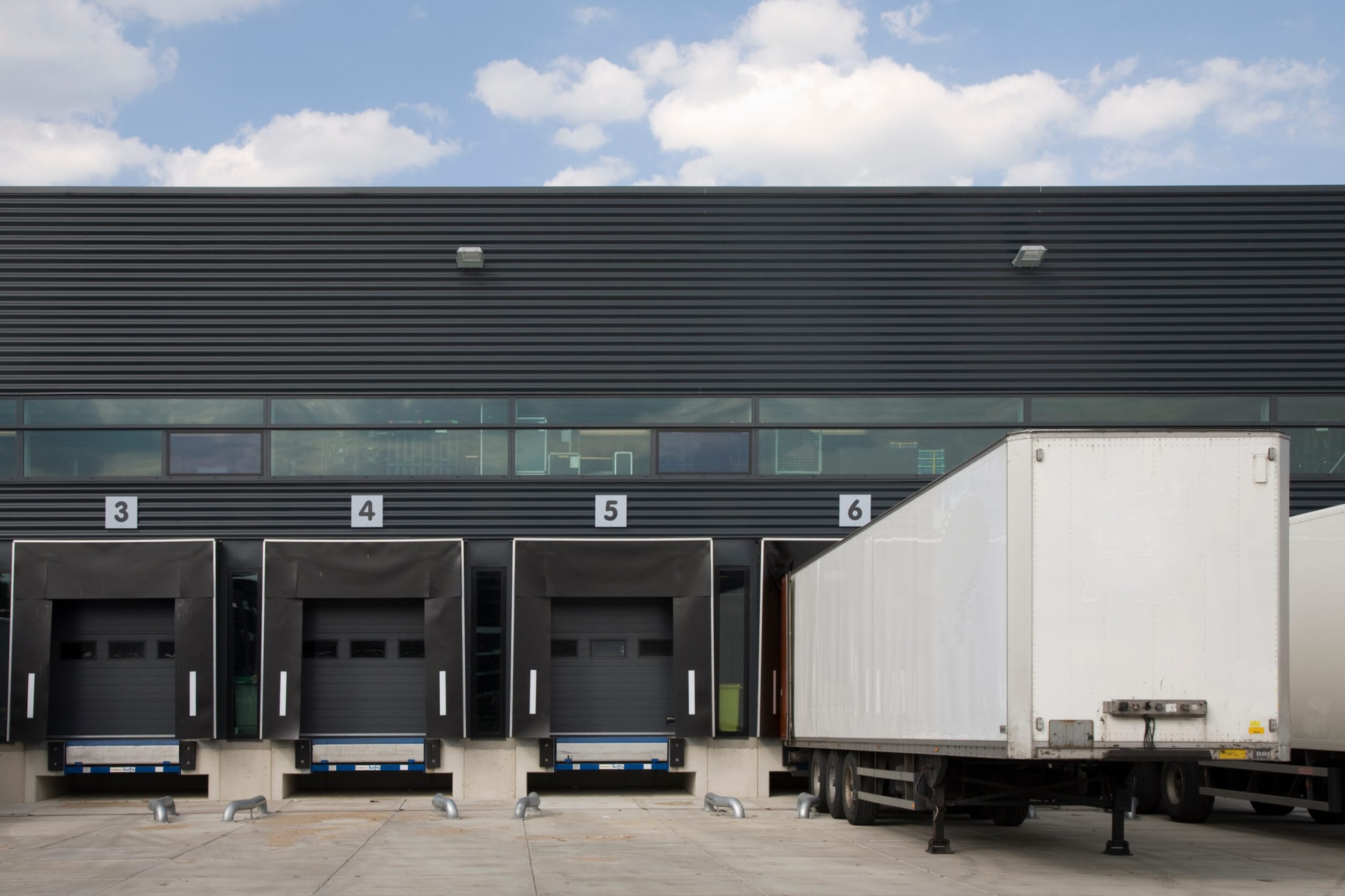 Loading bay entrance illustration with doors and lorries, depicting logistics operations.