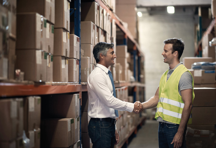 Shot of two men shaking hands in a large warehouse